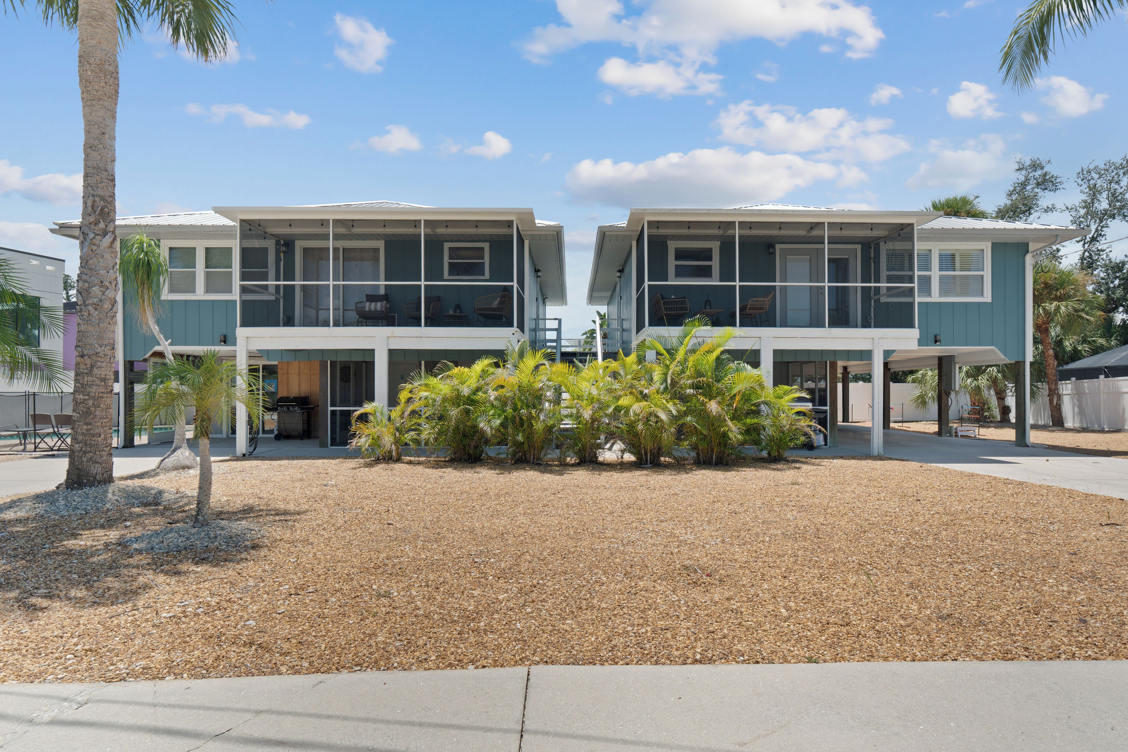 A two-story building with a covered patio area and a landscaped garden with palm trees.