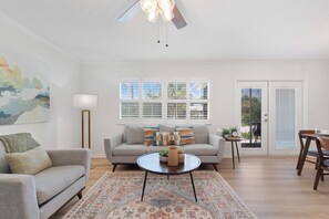 A living room with a sofa, coffee table, and a painting on the wall.