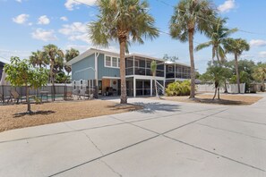 A two-story building with a pool, palm trees, and a clear sky.