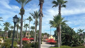Una zona de resort amb palmars alts, paraigües vermells i un jardí ben cuidat.