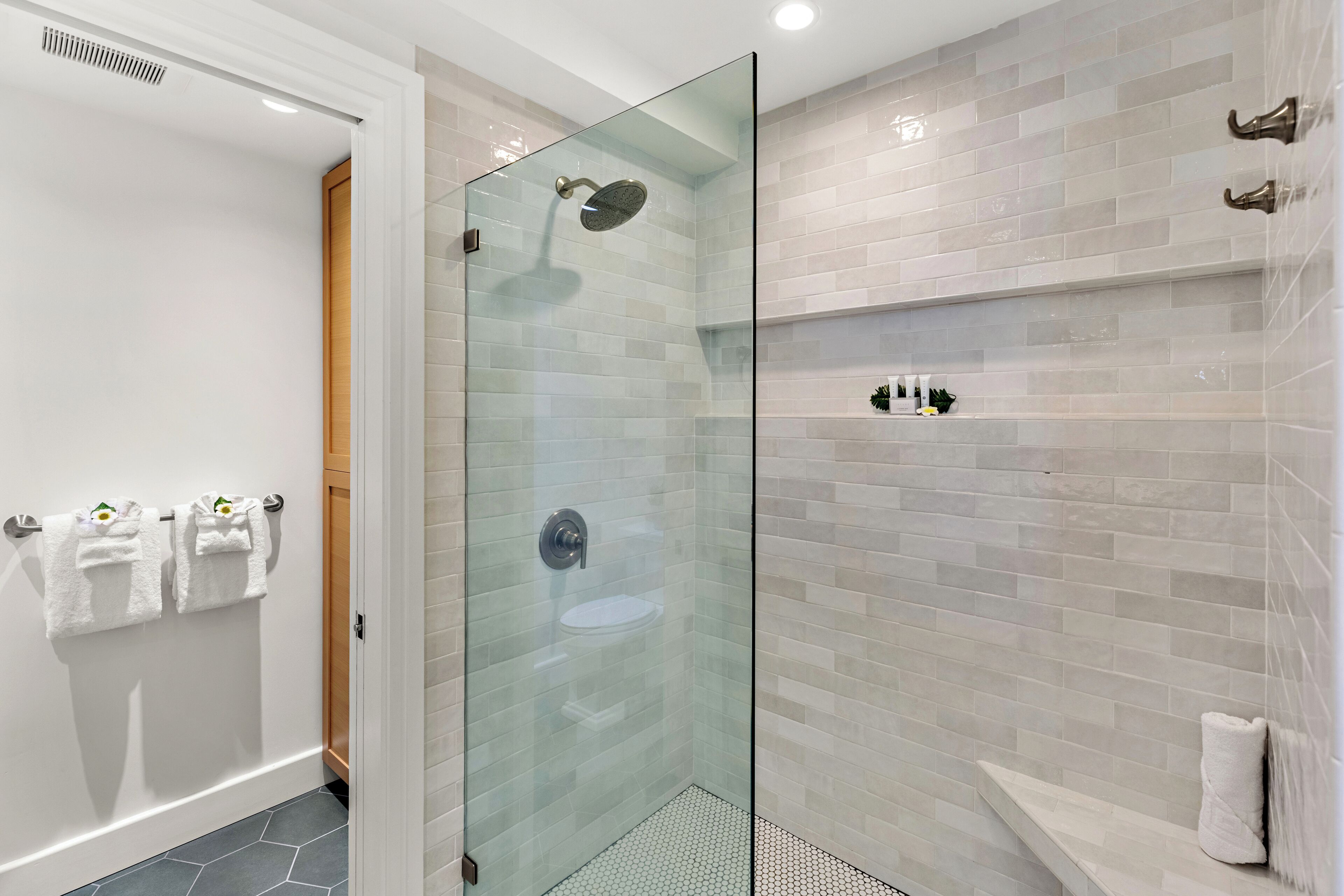 A modern bathroom with a glass-enclosed shower, a white sink, and a tiled wall.
