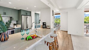 Eine moderne Küche mit einer großen Kochinsel, Barhocker und Blick ins Freie.