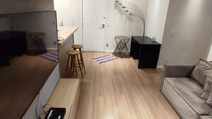Un soggiorno moderno con un divano, una TV, un tavolino e una poltrona.