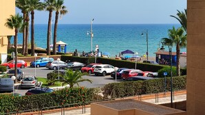 A coastal parking area with multiple cars, palm trees, and a view of the sea. - Beachfront Apartment with Pool & Sea View Terrace – Guadalmar Málaga (Churriana)