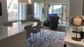 A modern kitchen with a dining area, large windows, and a view of the city. - Luxury City Seafront Apartment w Balcony (Helsinki)