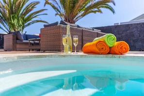 A poolside area with a wicker sofa, a stone wall, and a stack of rolled towels. - Villa Gisher - Three Bedroom Villa, Sleeps 6 (Montaña Roja)
