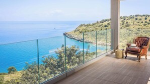 Ein Balkon mit freiem Blick auf das Meer und eine hügelige Landschaft.