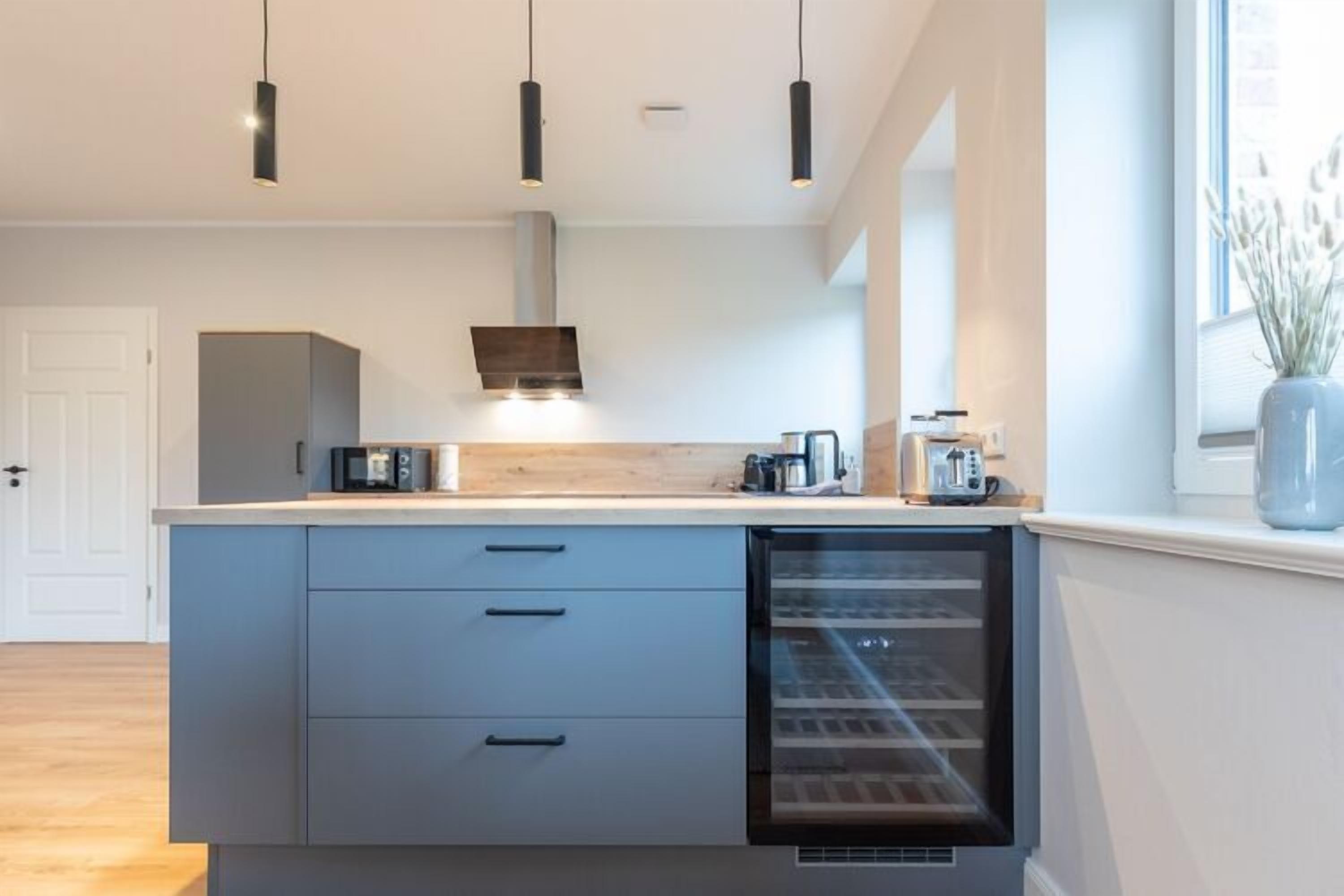 Eine moderne Küche mit einem eingebauten Kühlschrank, einer Mikrowelle und einer Kaffeemaschine auf der Arbeitsplatte.