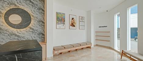 Un intérieur moderne avec un mur en marbre, un comptoir en marbre noir, un banc avec des coussins et des œuvres d’art encadrées accrochées au mur.