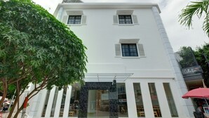 A white building with a glass entrance, a tree in front, and a sign that reads "Collection". - Collection O 90774 Homi Stay (Surakarta)