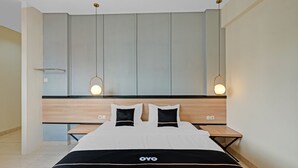 A modern hotel room with a large bed, bedside tables, and a headboard with built-in lighting. - Collection O 90774 Homi Stay (Surakarta)