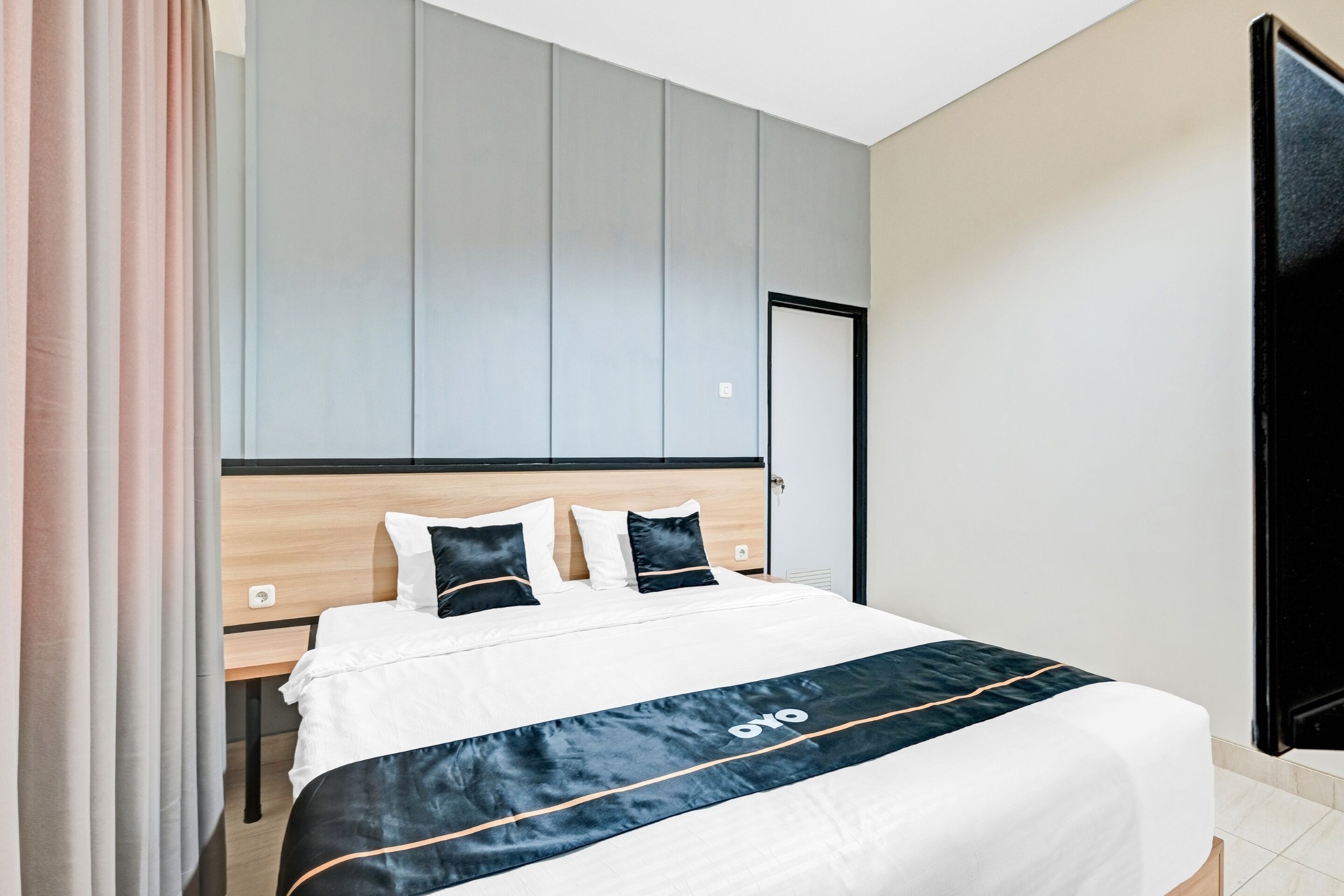 A modern hotel room with a bed, a nightstand, and a flat-screen TV.