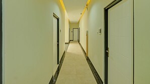A long, narrow hallway with doors on both sides, a tiled floor, and a ceiling light. - Collection O 90774 Homi Stay (Surakarta)