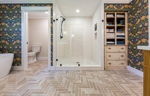 Un baño con ducha, inodoro y toallero.