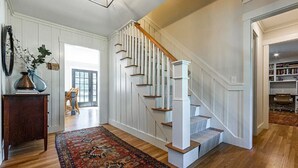 A staircase with white balusters and wooden steps leading to a landing. - Remodeled Beautiful 4-Bedroom Secluded Home in Downtown Bar Harbor! (Bar Harbor)