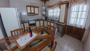 A kitchen with a dining table, chairs, a refrigerator, a stove, and a water heater.