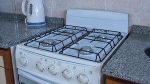A kitchen with a white gas stove, four burners, and a kettle on the countertop.