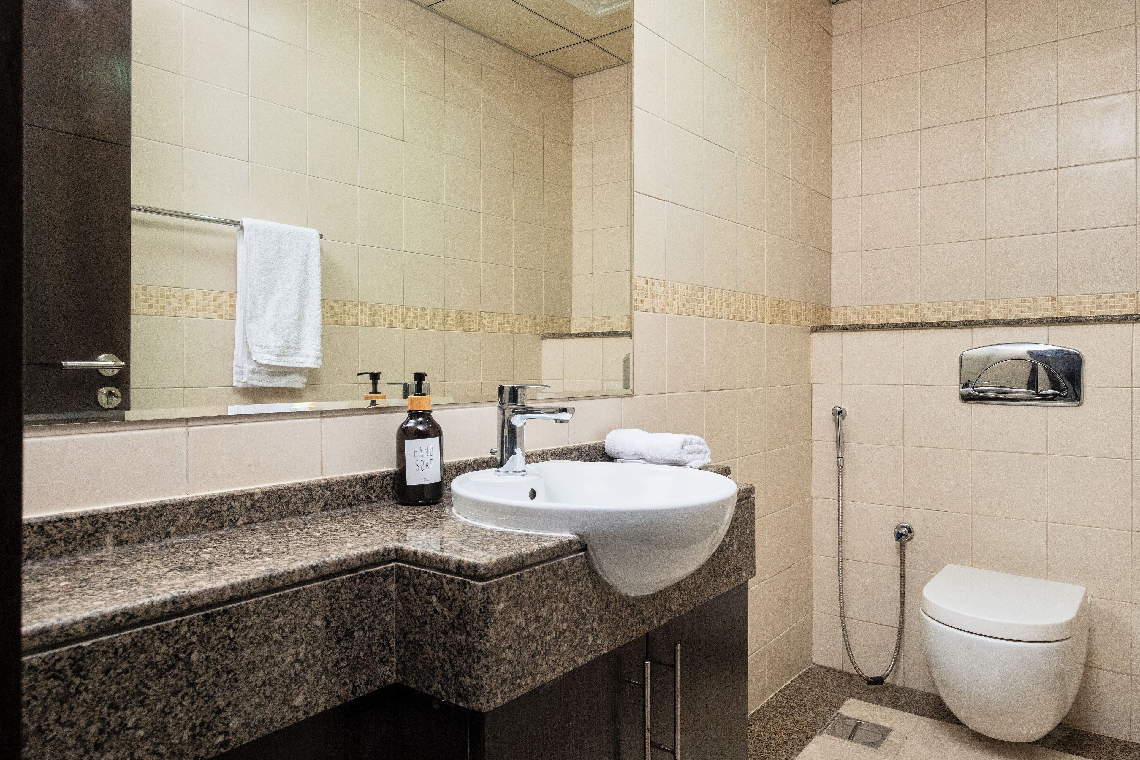 Een badkamer met een granieten aanrechtblad, een wit wastafel en een toilet.