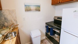 A compact kitchen with wooden cabinets, a stainless steel stove, and a white refrigerator.