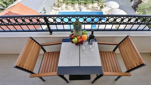 Un balcón con una mesa dispuesta para dos personas, con un frutero y dos copas de vino.