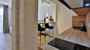 Una cocina moderna con estufa integrada, encimeras de madera y taburetes negros.