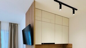 Una cocina compacta con televisión integrada, un lavamanos y armarios de madera.