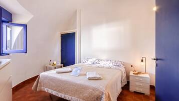 A bedroom with a bed, bedside table, and a window.