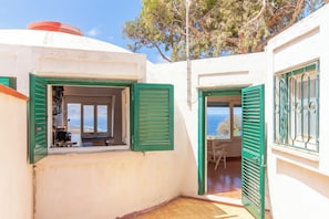 Un edificio blanco con contraventanas verdes, vista al mar y suelo de madera.