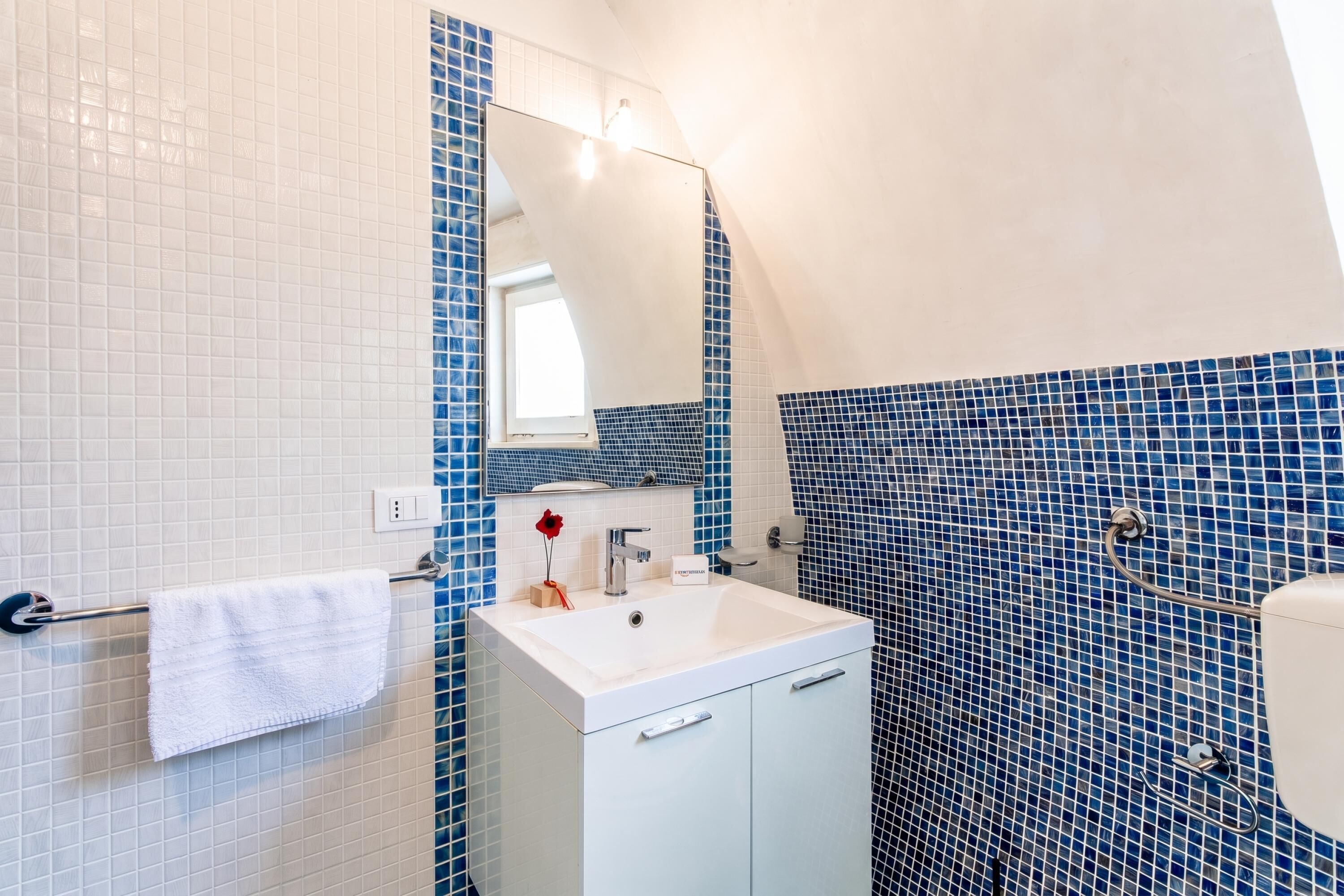 Une salle de bain avec un lavabo blanc, un miroir et un porte-serviettes.