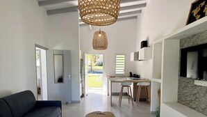 Ein modernes Wohnzimmer mit Sofa, Couchtisch und Essbereich mit Stühlen und Küchenzeile.