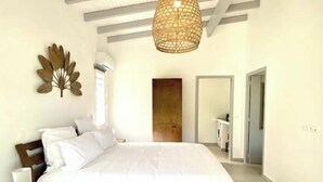 Ein Schlafzimmer mit einem großen Bett, einem Nachttisch mit Lampe, einem Wanddekor und einer Pendelleuchte.