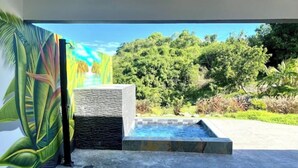 Ein moderner Poolbereich im Freien mit einer Steinmauer und Blick auf eine üppige, grüne Landschaft.