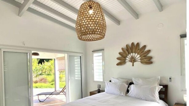 Ein Schlafzimmer mit einem großen Bett, einem Deckenventilator und Blick ins Freie.