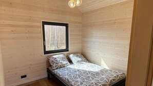 A small, cozy room with a bed, a window, and wooden walls. - Single-story holiday homes very close to the beach (Wicie)