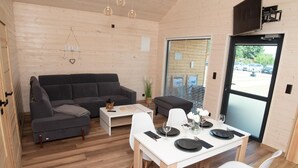 A modern interior with a grey sofa, white dining table, and a large window. - Single-story holiday homes very close to the beach (Wicie)