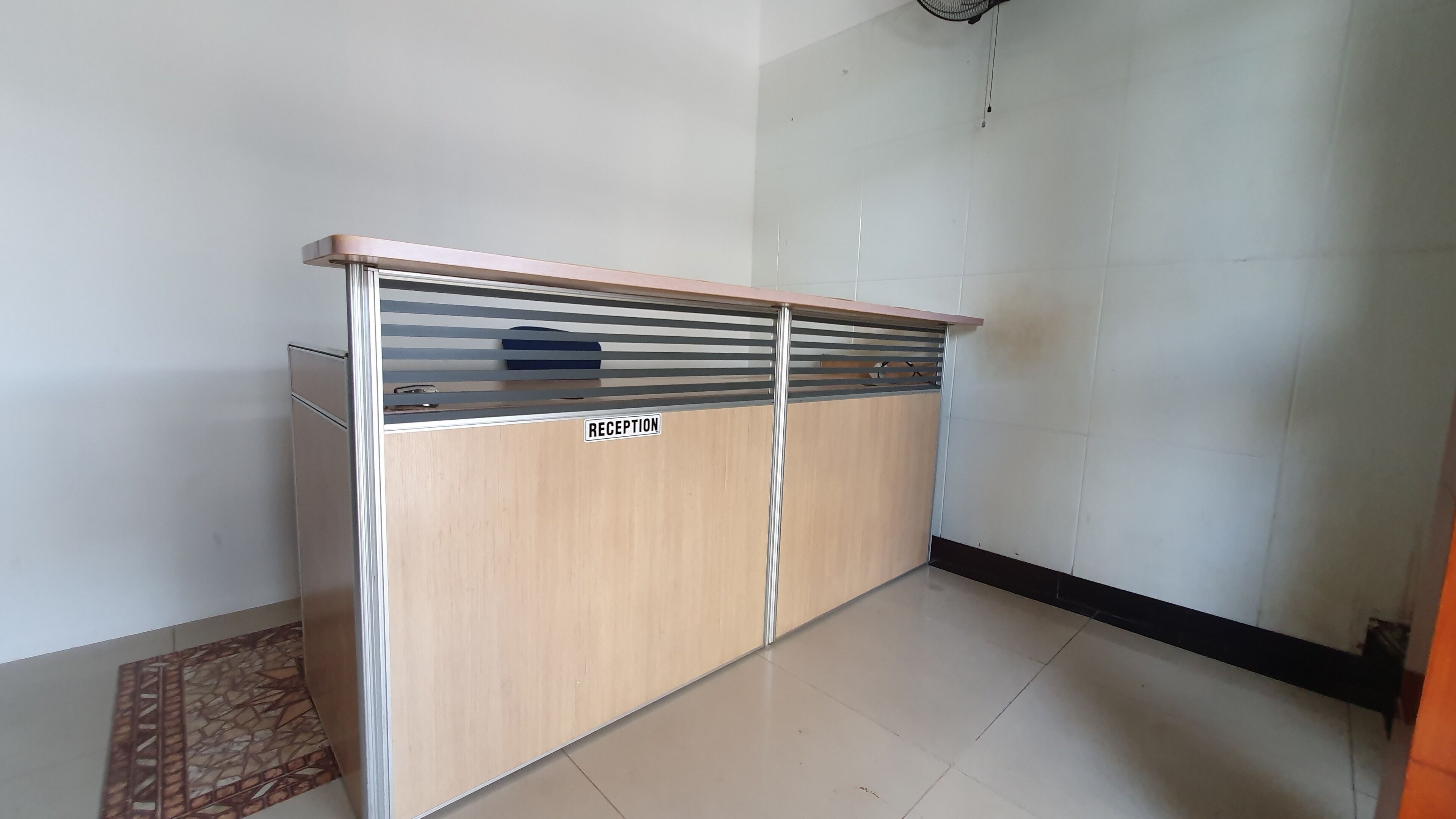 Un área de recepción con un mostrador de madera, un cartel que dice 