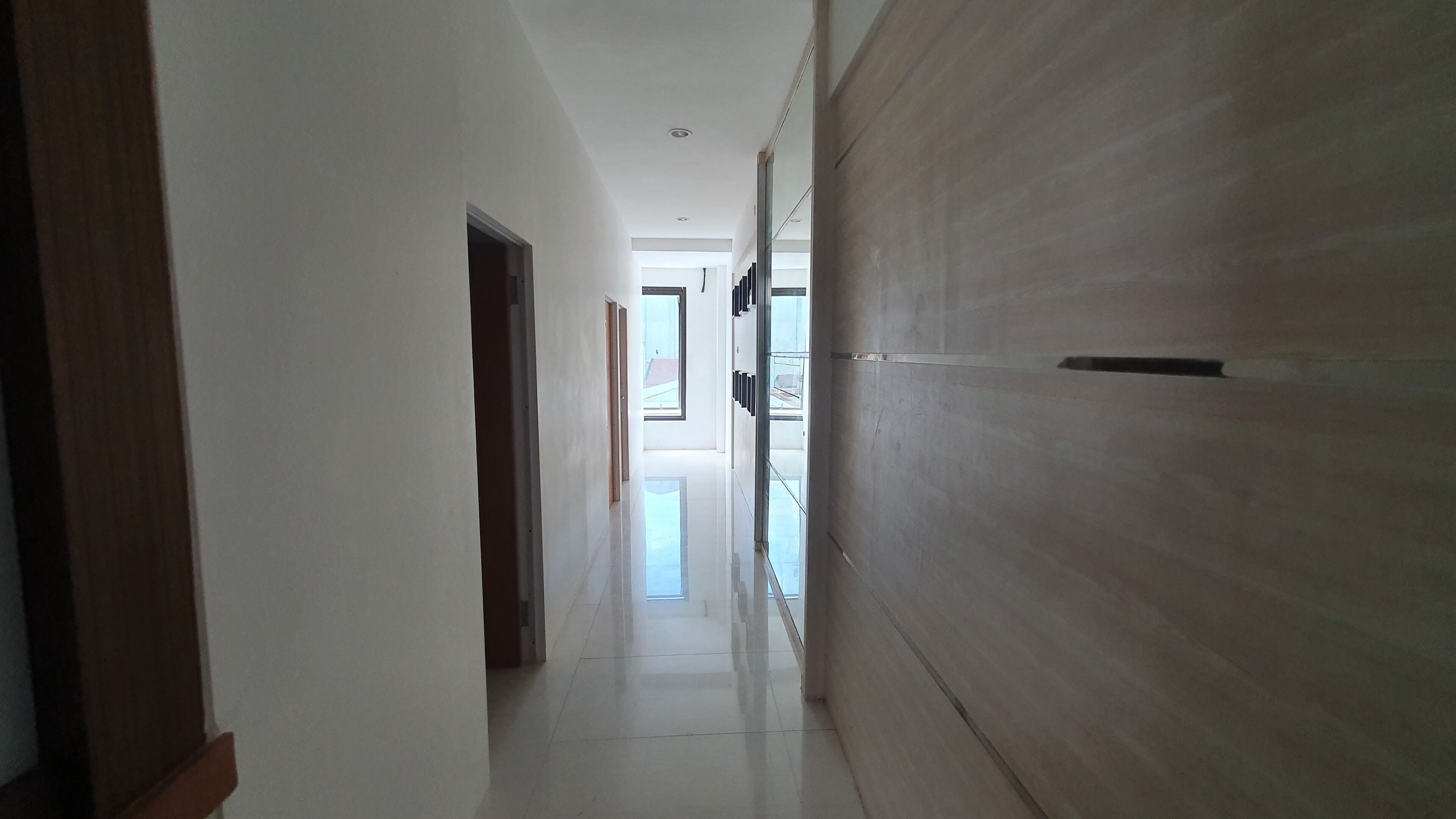 A hallway with a wooden door on the right and a white door on the left.