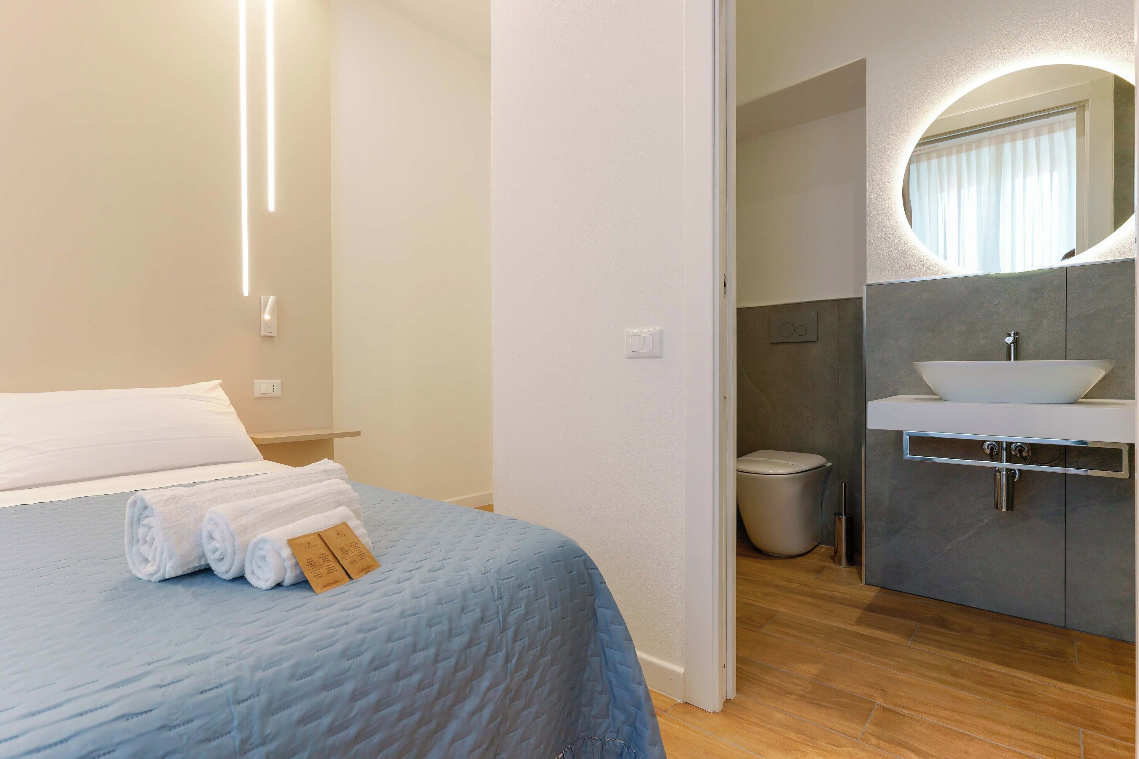 A hotel room with a bed, a bathroom with a sink and mirror, and a toilet.