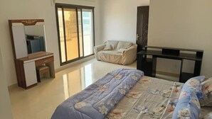 Een slaapkamer met een bed, een bureau, een stoel, een kledingkast en een schuifdeur van glas.