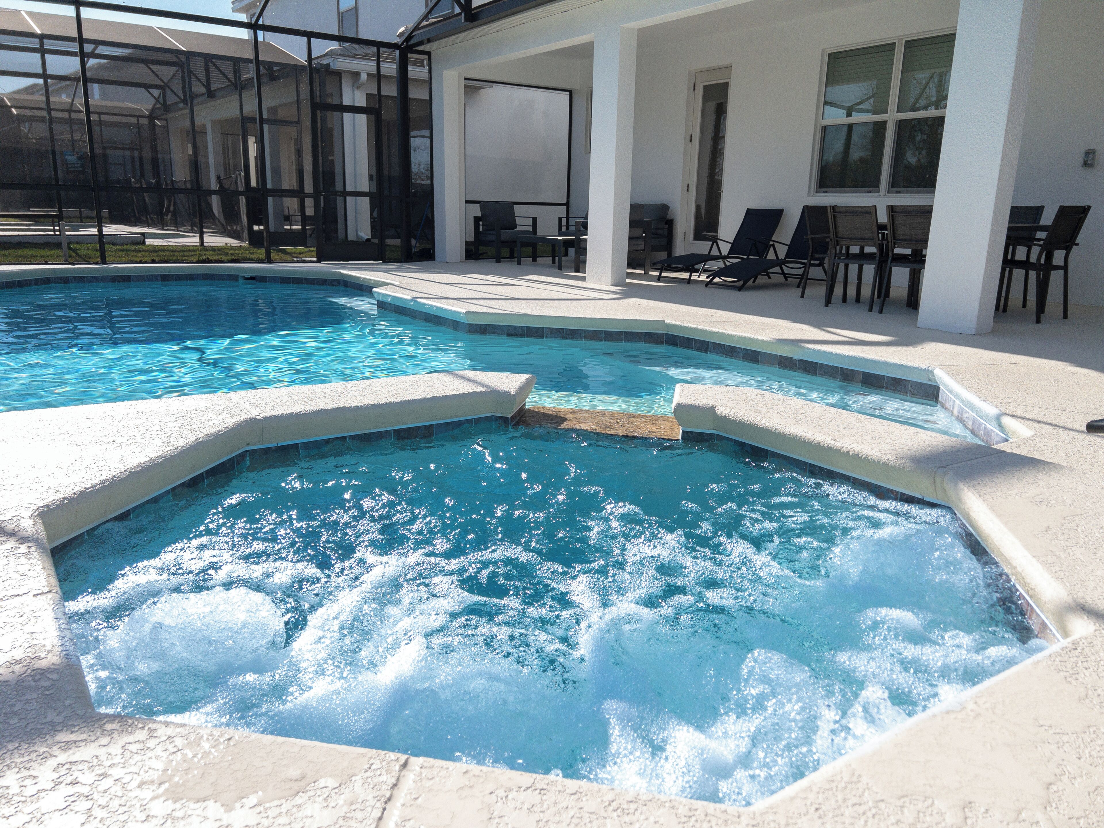Ein Swimmingpool mit Whirlpoolbereich, umgeben von Liegestühlen und einer überdachten Terrasse.