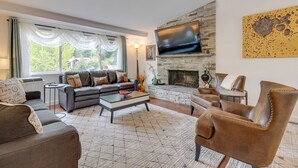 Una sala de estar moderna con chimenea, sofás de cuero y un televisor de pantalla plana grande montado en la pared.