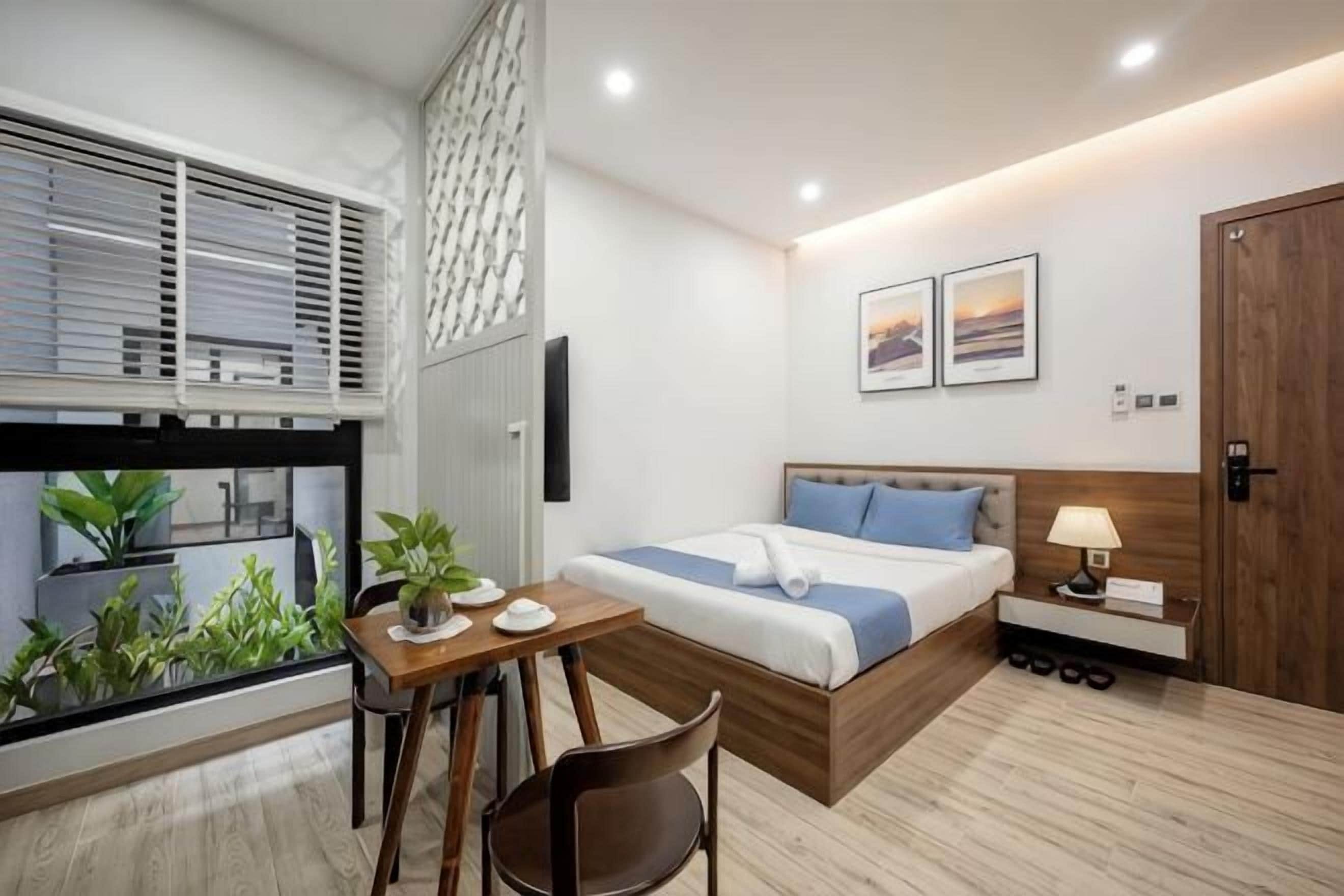Ein modernes Schlafzimmer mit Bett, Nachttisch, Lampe und Blick durch ein Fenster.