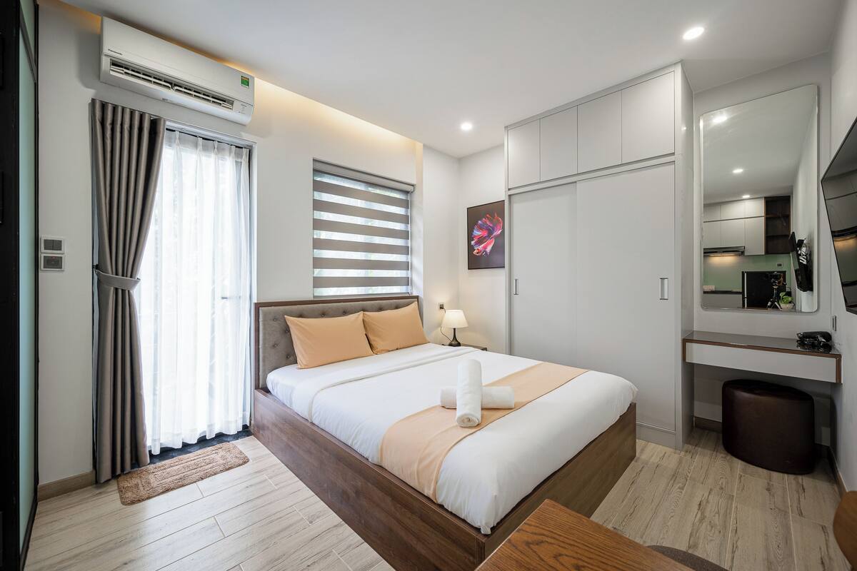 A modern bedroom with a bed, bedside table, and a mirror.