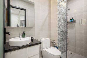 Ein modernes Badezimmer mit einem weißen Waschbecken, einer Toilette und einer Duschkabine.