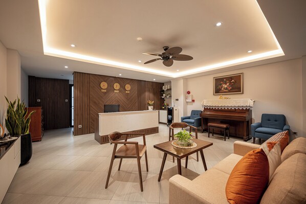 Ein modernes Wohnzimmer mit einer Couch, Sesseln, einem Couchtisch und einem Klavier.