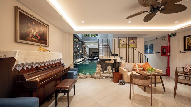 A living room with a piano, a sofa, a dining table, and a staircase leading to another level.