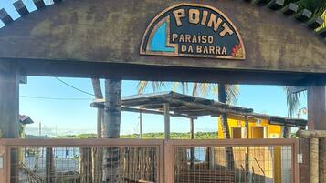 Ein hölzernes Tor mit einem Schild darüber, auf dem „POINT PARAISO DA BARRA“ steht.