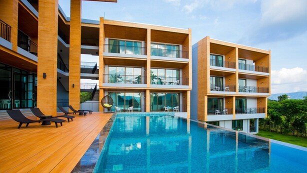 A modern hotel with a pool area, multiple balconies, and outdoor seating. - The Earth Anthioch Khao Yai (Pak Chong)