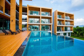 A modern hotel with a pool area, multiple balconies, and outdoor seating. - The Earth Anthioch Khao Yai (Pak Chong)