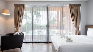 A hotel room with a bed, a chair, a lamp, and a view of the outside. - The Earth Anthioch Khao Yai (Pak Chong)